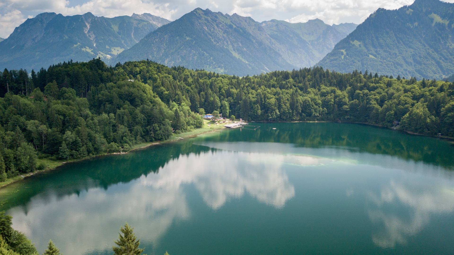 klarer Bergsee mit Wolkenspiegelung im Sommer