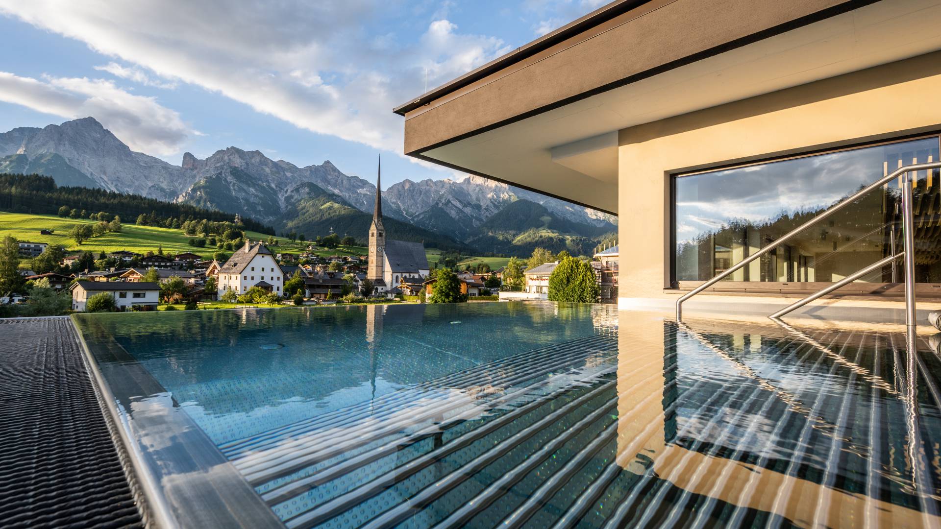 Infinitypool mit Aussicht auf Kirche und Berge