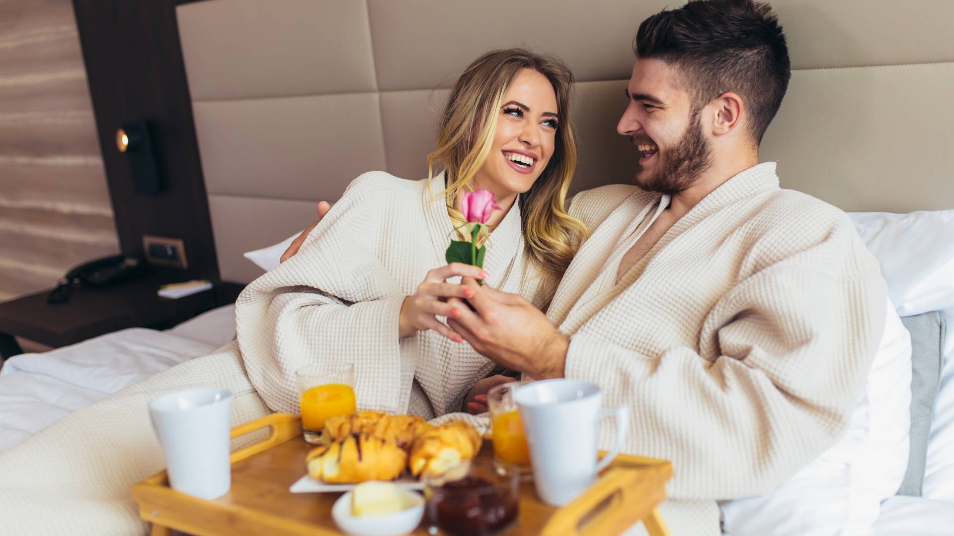 Mann und Frau mit Frühstück im Bett