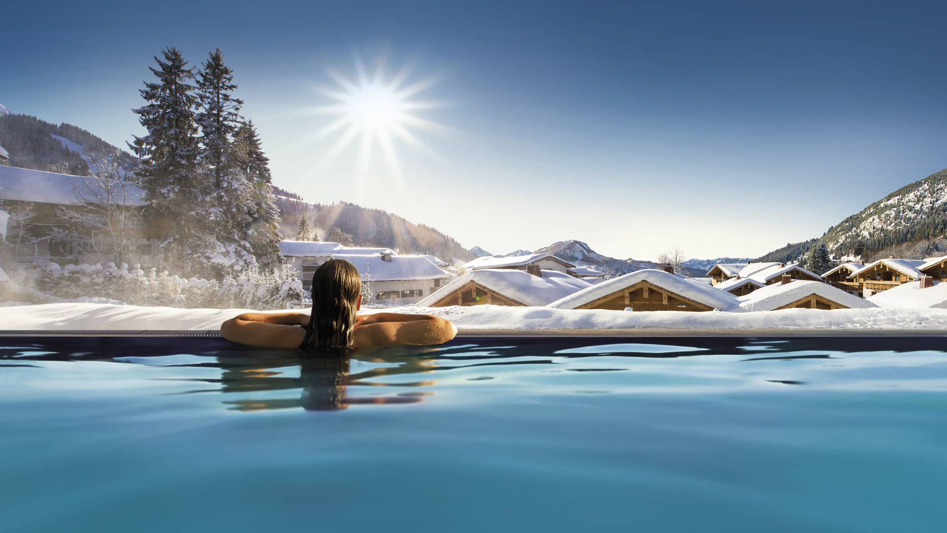 Woman in outdoor pool with mountain view in winter