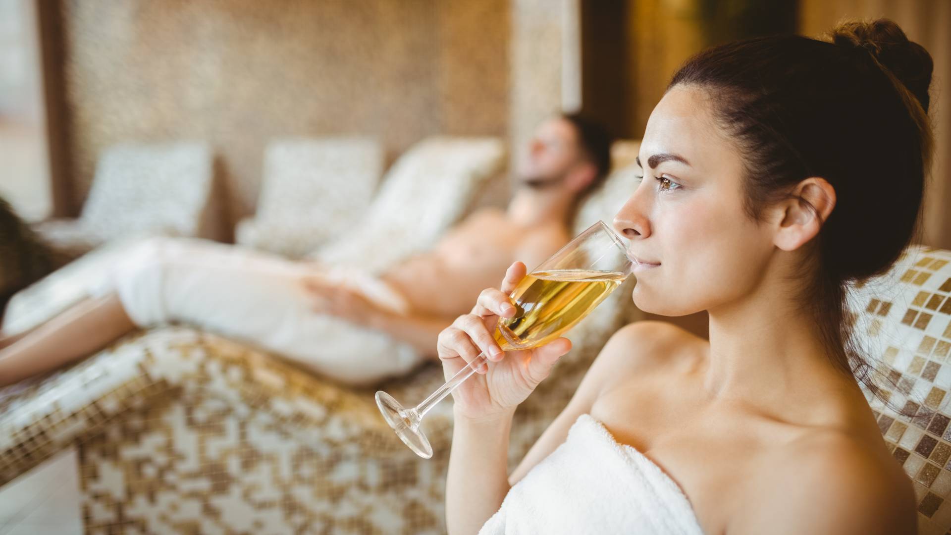 Woman on a heated bench drinks a glass of sparkling wine