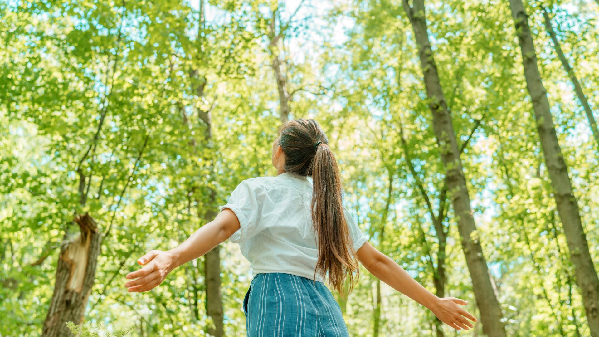 Woman stands in the forest and enjoys the fresh air and nature in spring