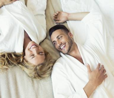Frau und Mann liegen im Bett und lachen