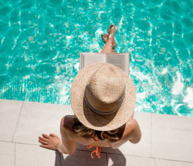 Woman sitting by the pool reading a book