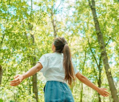 Woman stands in the forest and enjoys the fresh air and nature in spring