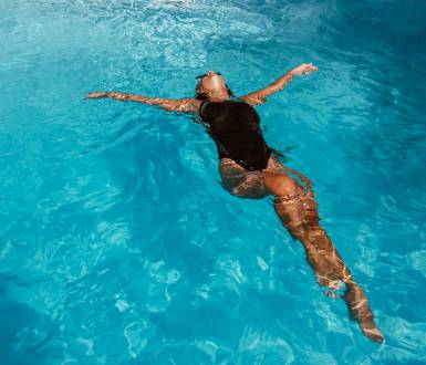 Frau schwimmt in glitzernden Pool an einem heißen Sommertag