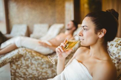 Frau trinkt ein Glas Sekt im Wellnessbereich