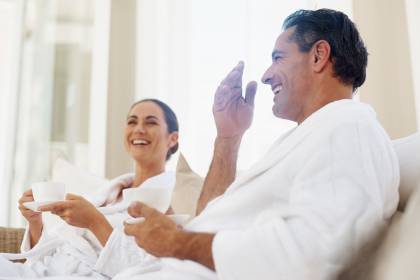 Man and woman sitting in spa, laughing and drinking a cup of coffee