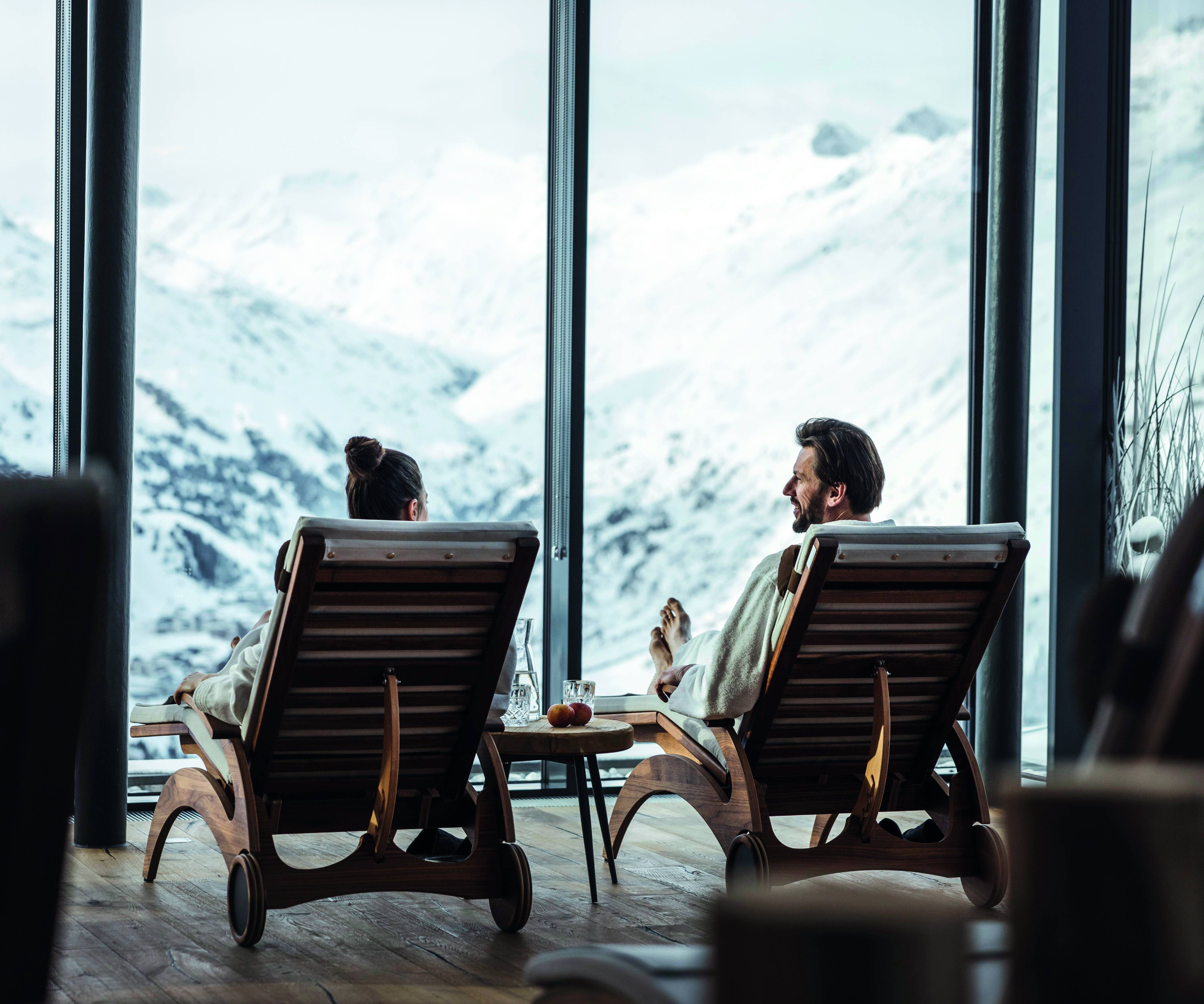 Paar unterhält sich in Ruheraum Blick auf schneebedeckte Berge