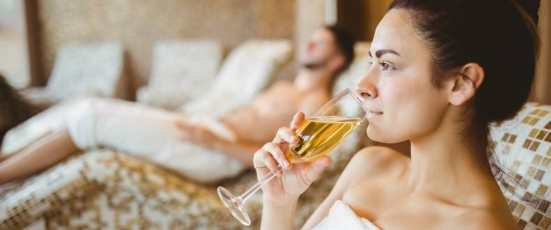 Woman on a heated bench drinks a glass of sparkling wine
