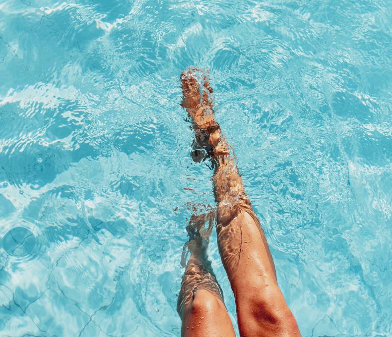 beautiful woman legs splashing in the pool